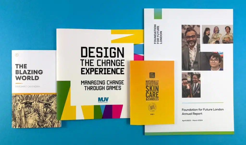 Books printed at Ex Why Zed featuring 'The Blazing World' by Margaret Cavendish, 'Design the Change Experience,' 'Naturally Effective Skin Care & Candles,' and the Foundation for Future London Annual Report, photographed against a blue background.