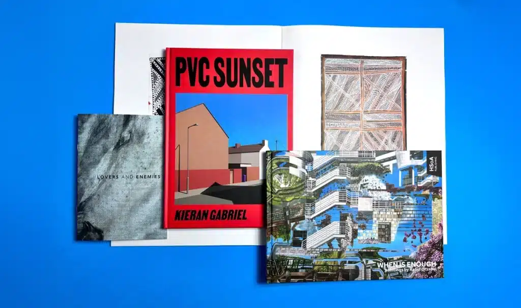 A stack of artist catalogues printed by Ex Why Zed featuring vibrant covers and precise binding