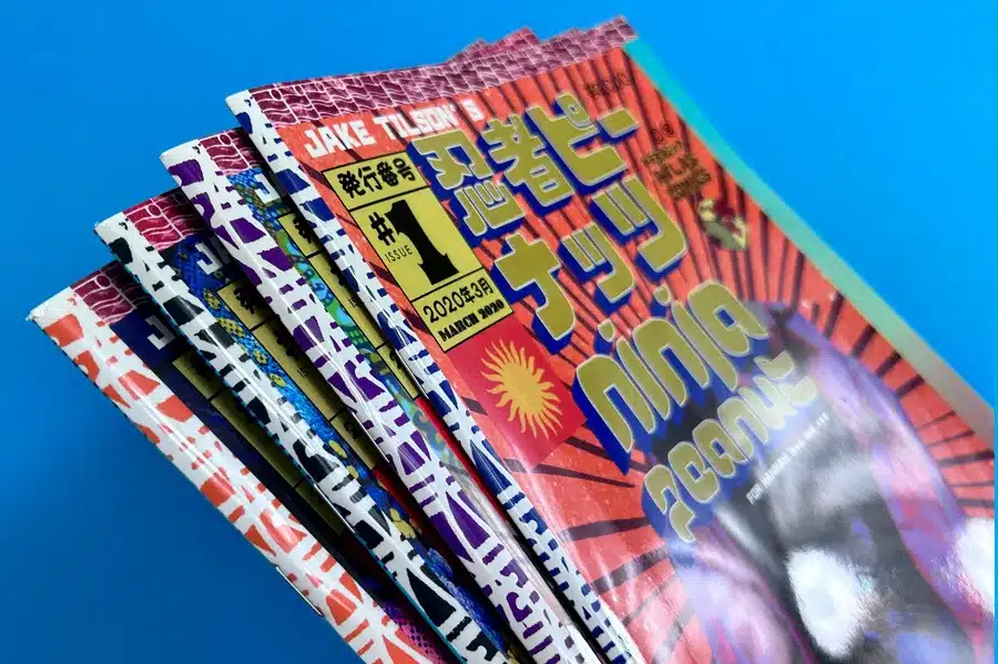 Professionally printed comic books from Ex Why Zed, displayed on a table.
