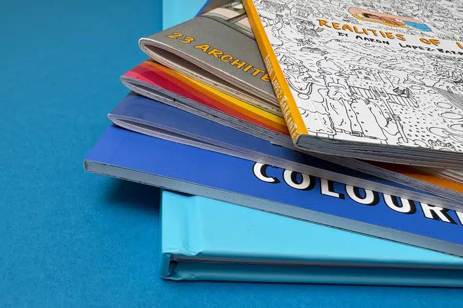 Six coloring books side by side, one with a spiral binding and another with perfect binding, showing different binding options for print.