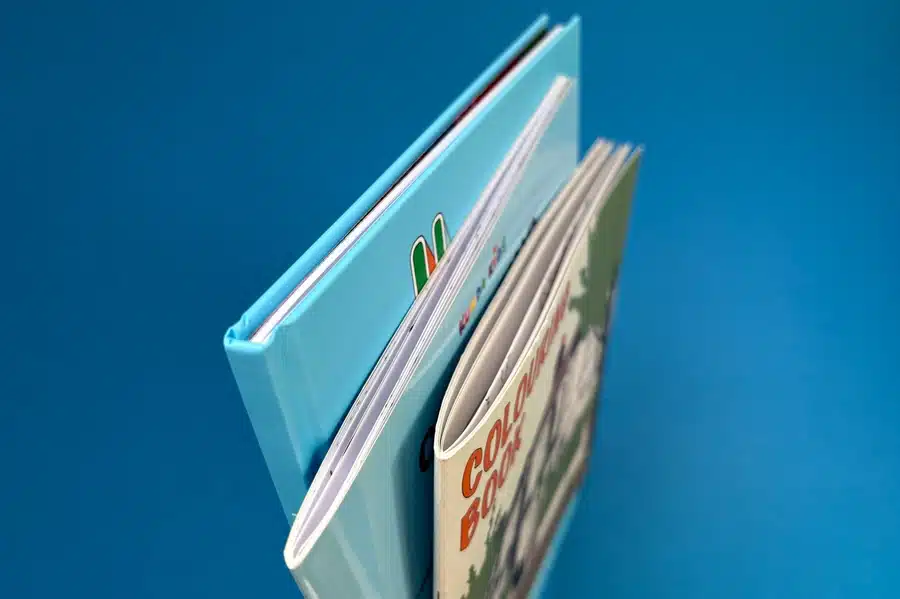 Three coloring books side by side, one with a spiral binding and another with perfect binding, showing different binding options for print.