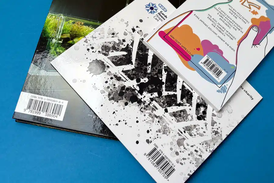 A stack of self-published books with ISBN barcodes visible