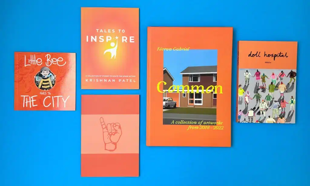 Self-published books on a desk with an author making notes