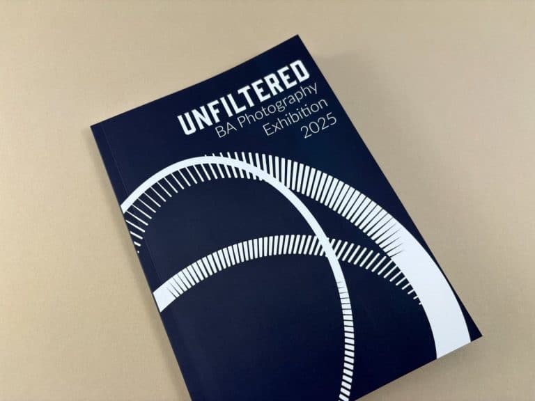 Dark navy perfect bound BA Photography degree show catalogue titled Unfiltered with bold white typography and circular graphic motif.