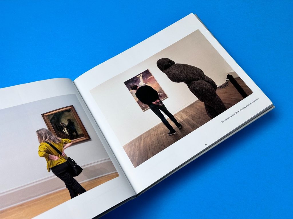 Open fine art photo book showing gallery photography spreads on a vivid blue background.