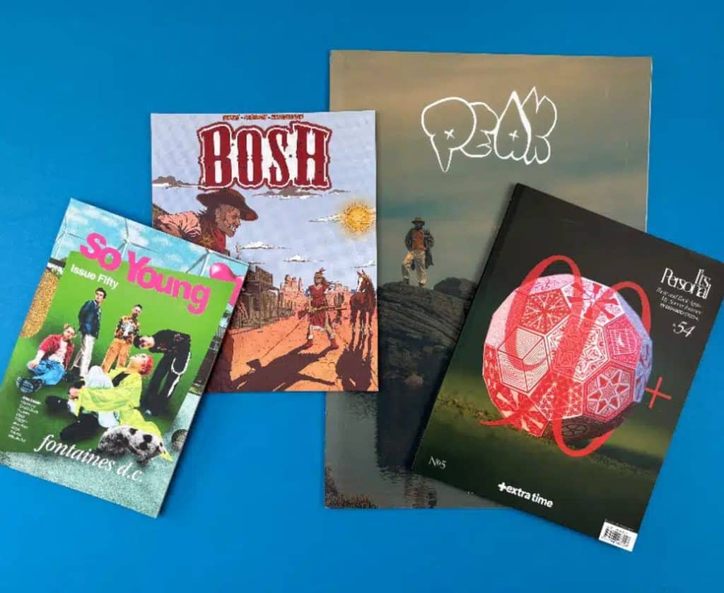 Creative magazines and zines laid out on a blue table for a Nottingham magazine printing guide.