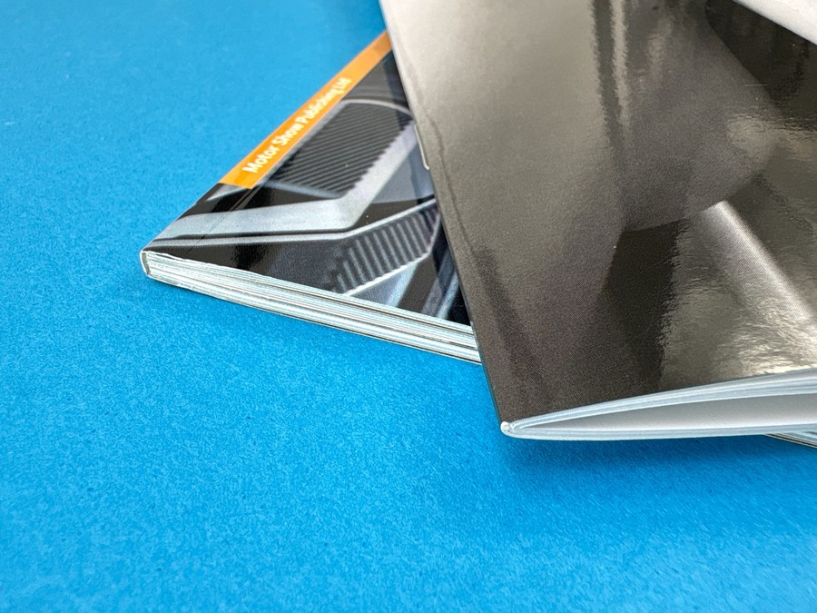 Close-up of stacked magazine bindings showing folded and perfect bound spines on a blue surface.
