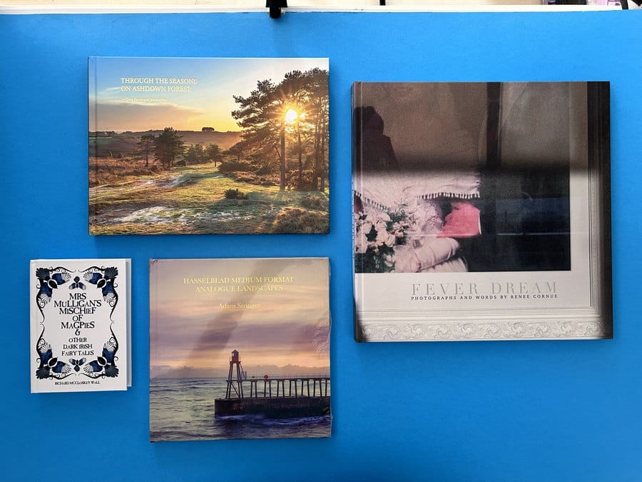 A range of printed photo books and paperbacks showing how paper stock, colour printing and binding choices change the cost per copy.