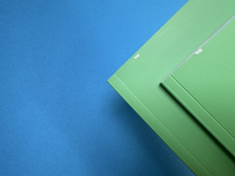 Two green perfect bound book covers with the word ‘top’ sitting right on the trimmed edge.