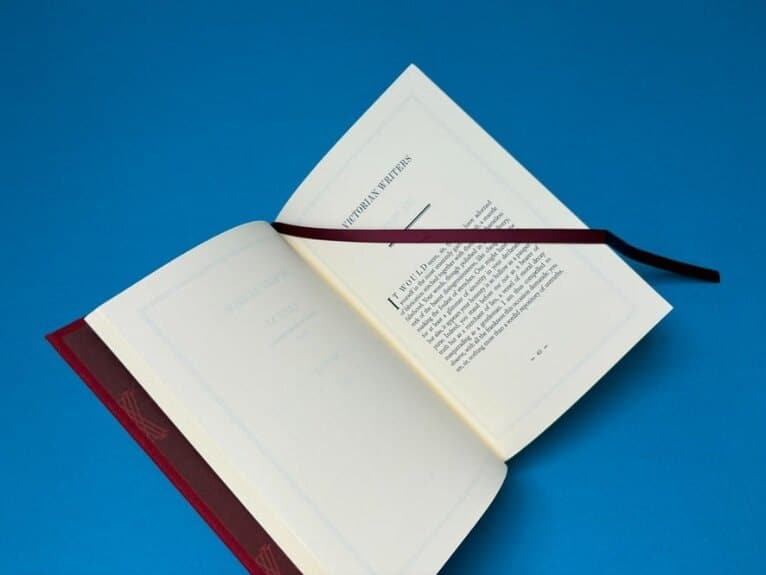 An Ex Why Zed printed hardback opened flat on a blue background, showing the colour accuracy and finishing quality behind every print order.