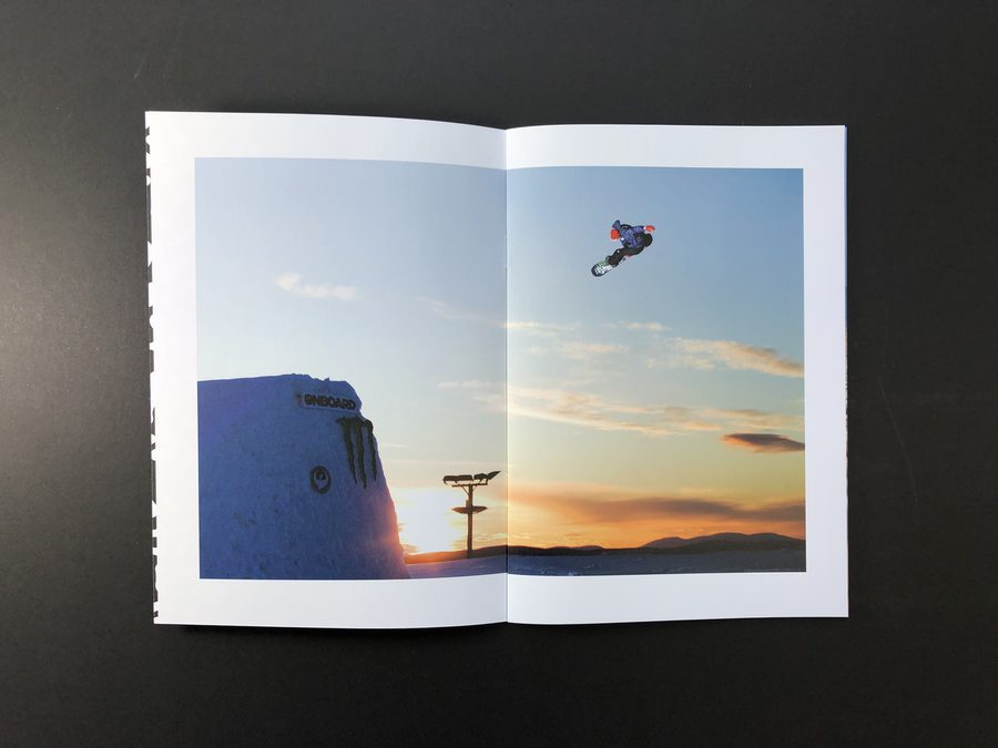 A stapled A5 zine lying completely flat, with a snowboarding photo running across the full double-page spread.