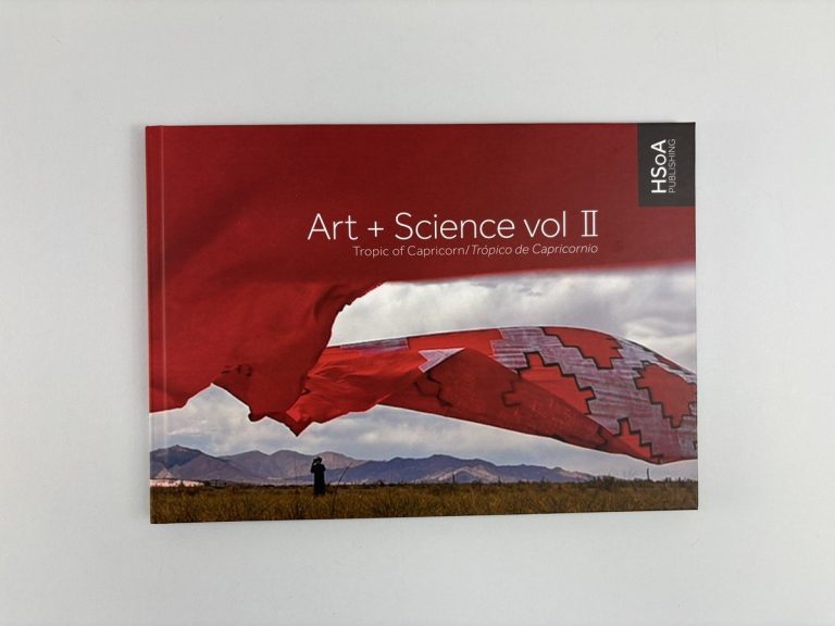 A4 landscape hardback cover of Art + Science vol II, Tropic of Capricorn: a red fabric sculpture streaming over mountains.